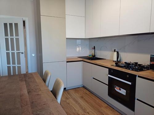 a kitchen with white cabinets and a table with chairs at Air-Moldova N1 in Chişinău