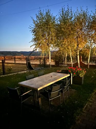 un tavolo e sedie di legno in un cortile con fiori di Noclegi u Alicji a Wola Kalinowska