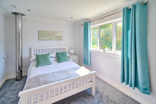 a bedroom with a white bed with blue curtains at Charming 2BD House - Parking & Garden in Oban in Oban