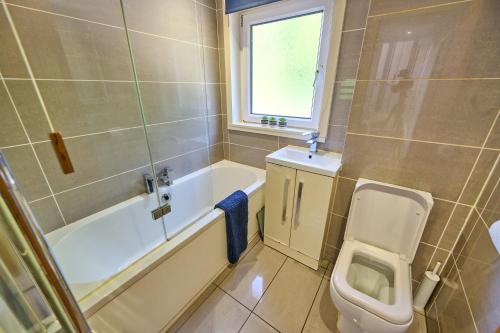 a bathroom with a toilet and a tub and a sink at Charming 2BD House - Parking & Garden in Oban in Oban