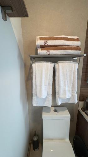 a bathroom with a white toilet and towels at Luxury apartment 10 min to Airport Be Cariari Condo #402 in La Asunción