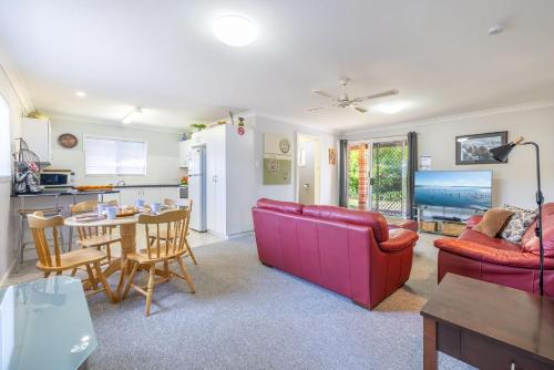 a living room with a red couch and a table at Lorikeet Retreat 2 Pet Friendly Air Conditioned Holiday House in Shoal Bay