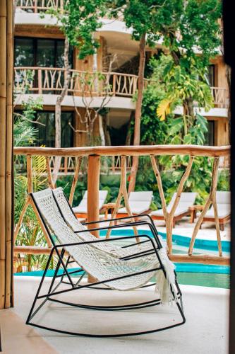 a chair sitting on a porch next to a pool at Kan Tulum Hotel in Tulum