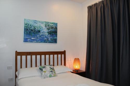 a bedroom with a bed with a lamp and a window at Pacific Crown Hotel in Honiara
