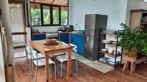 a kitchen with a wooden table and a refrigerator at Tropical - Airy, open plan apartment in heart of Santa Teresa in Santa Teresa Beach