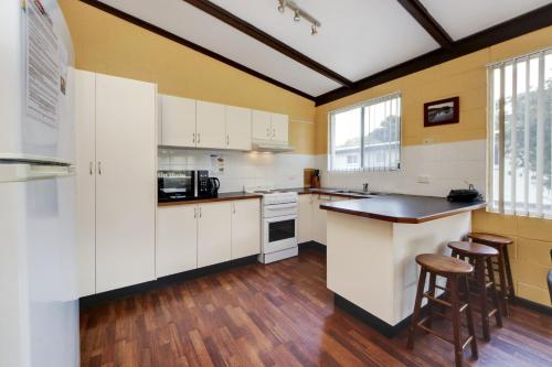 a kitchen with white cabinets and a counter with stools at Bella Beach 575-77 Straight St Hat Head in Hat Head