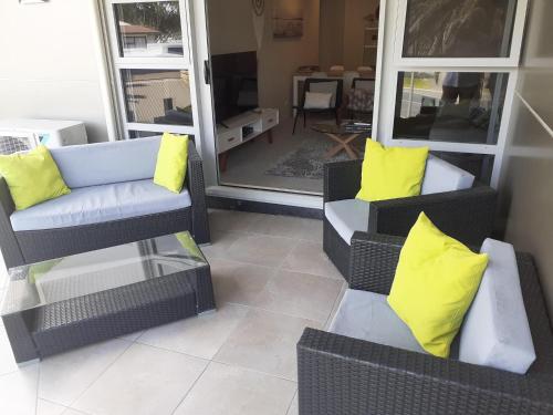 a living room with two chairs and yellow pillows at Esplanade Apartments in Whitianga