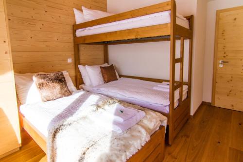 two bunk beds in a room with wooden walls at Chalet Les Rahâs by Mrs Miggins in Grimentz