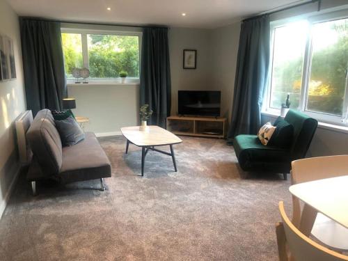 a living room with two chairs and a couch and a table at Bronte Country - 2 Bed Apartment near Cliffe Castle in Keighley