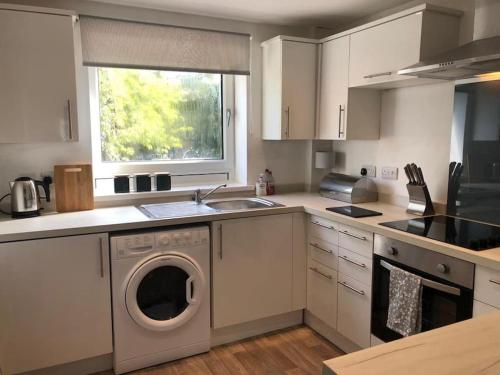 a kitchen with a washing machine and a sink at Bronte Country - 2 Bed Apartment near Cliffe Castle in Keighley