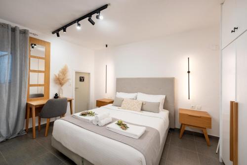 a bedroom with a large white bed and a desk at Hypnosis Beachside Villa with Private Heated Pool in Georgioupolis