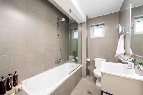 a bathroom with a tub and a toilet and a sink at Hypnosis Beachside Villa with Private Heated Pool in Georgioupolis