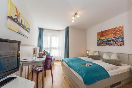 Schlafzimmer mit einem Bett, einem Schreibtisch und einem TV in der Unterkunft Hotel AMENITY in München