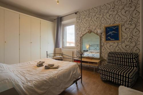 a bedroom with a bed and a chair and a mirror at L'originario Salviano Family Apartment in Livorno