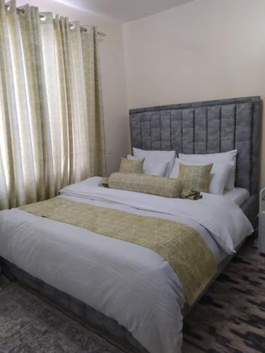 a bedroom with a large bed with white sheets and pillows at ZOE HOMES Home Away From Home For Cozy And Modern Stay in Nairobi