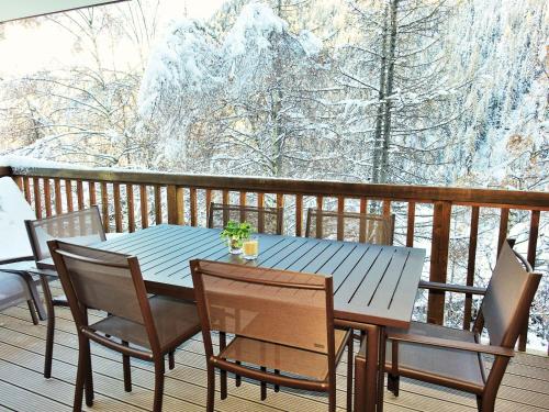 a table and chairs on a deck with snow covered trees at Chalet Les Rahâs by Mrs Miggins in Grimentz