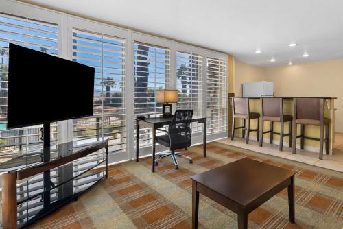 a living room with a flat screen tv and a desk at Best Western Date Tree Hotel in Indio