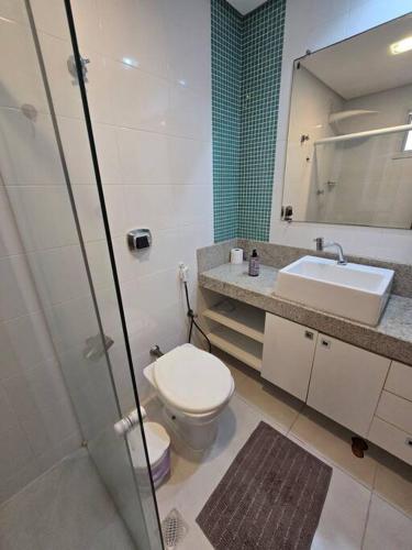 a bathroom with a toilet and a sink and a mirror at Lindo Apt Beira Mar Guarapari in Guarapari