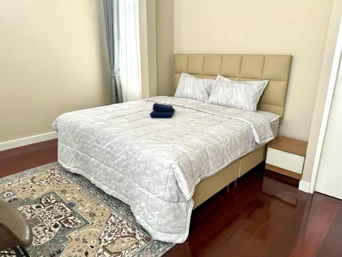 a bed with a white comforter and a blue hat on it at EM HOME Sukhumvit Bangkok - near Terminal 21, EM District Malls, BTS and MRT Lines in Bangkok
