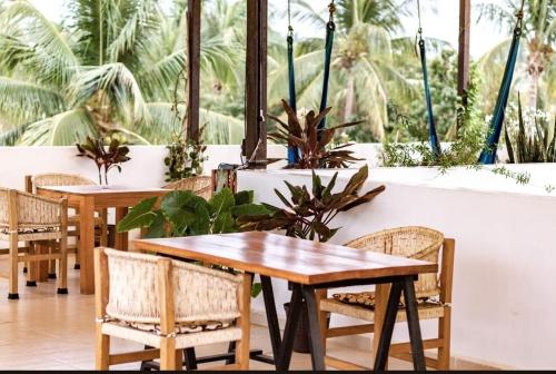 a restaurant with two tables and chairs and plants at Casa De La Palmera in Brisas de Zicatela