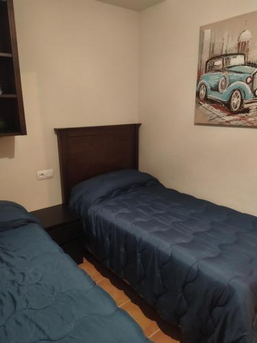 a bedroom with two beds and a painting of a car at Casa Villa Duque in El Bosque
