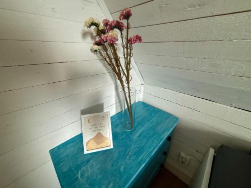 a blue table with a vase of flowers and a card at Ferienhaus Istaby in Sölvesborg
