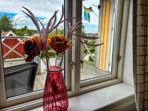 a red vase with flowers sitting on a window sill at Ferienhaus Istaby in Sölvesborg