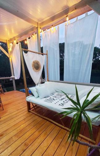 a bed on a deck with a hammock on a porch at Love Room Les sens'même in Bouloupari