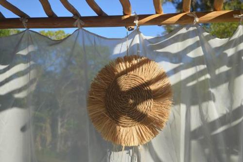 a straw hat is hanging from a curtain at Love Room Les sens'même in Bouloupari