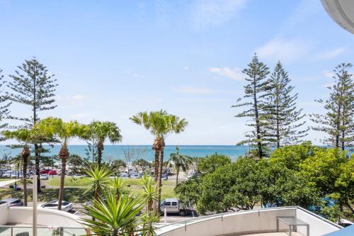 a view of a park with palm trees and the ocean at Malibu Apartments in Mooloolaba