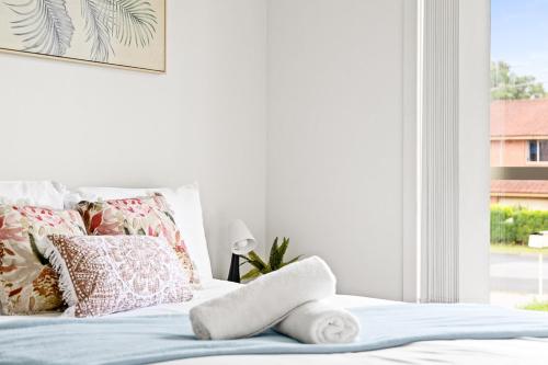 a white bedroom with a bed with pillows and a window at Cozy Double Room in Panania - Close to Stations & Stores - Shared Bathroom in Panania