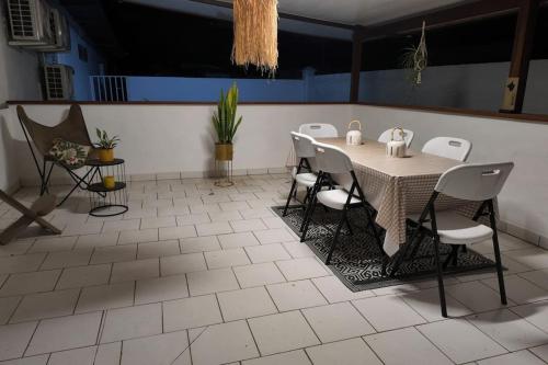 a dining room with a table and white chairs at T3 meublé avec parking et jardin in Matoury