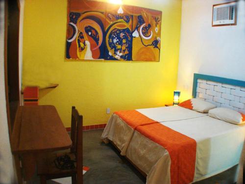 a bedroom with a bed and a painting on the wall at Art Hotel Aos Sinos Dos Anjos in Arraial d'Ajuda