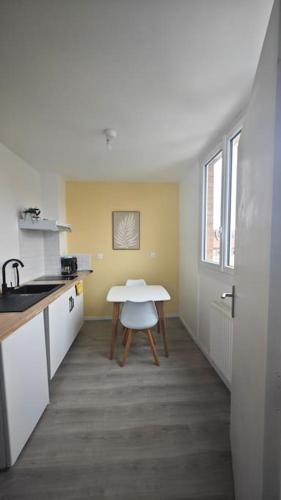 - une cuisine avec une table et une table blanche dans l'établissement Escapade Culturelle - Studio Roubaix, à Roubaix