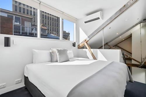 a white bedroom with a large bed and a window at Gibson Mill waterfront loft apartment - 304 in Hobart