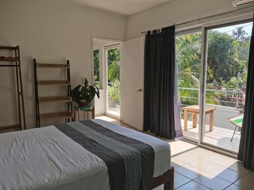 a bedroom with a bed and a large window at Casa De La Palmera in Brisas de Zicatela