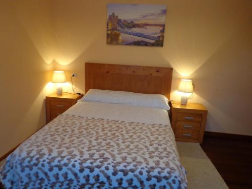a bedroom with a bed with two lights on two night stands at Apartamento Rosalia in Milladoiro