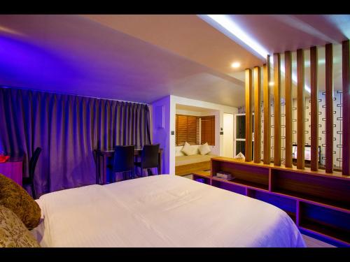 a bedroom with a white bed and purple lighting at Ripple Beach Inn in Hulhumale