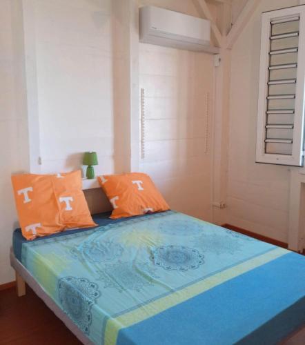 un letto con lenzuola arancioni e blu in una stanza di Hibiscus Location a Le Vauclin