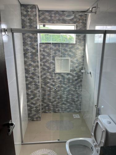 a bathroom with a shower with a toilet and a window at Apartamento no Centro in Paracatu