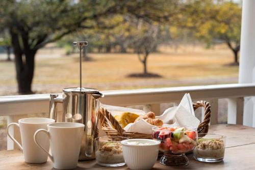 a table with a basket of food and cups on a porch at The Carriages Boutique Hotel and Vineyard in Pokolbin