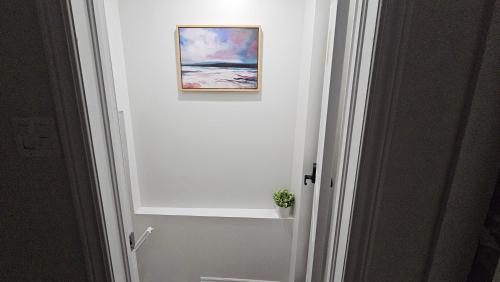 a painting on the wall of a bathroom with a plant at Garden Ave Home 1mins to HWY 403 in Brantford