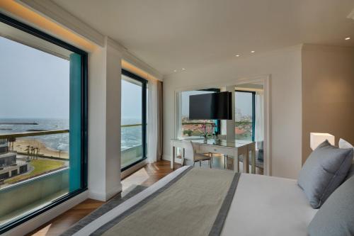 a bedroom with a bed and a desk with a large window at Herbert Samuel Okeanos Suites Herzilya in Herzelia 
