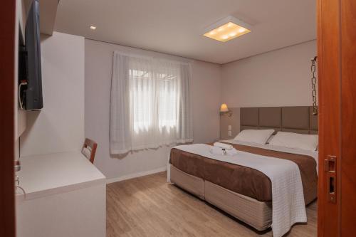 a hotel room with a bed and a window at Pousada Zammá Gramado in Gramado