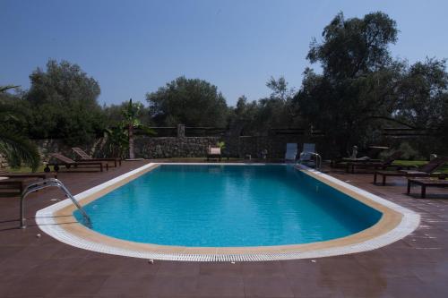 a swimming pool in a yard with benches around it at 5 Stars Villas in Svoronata