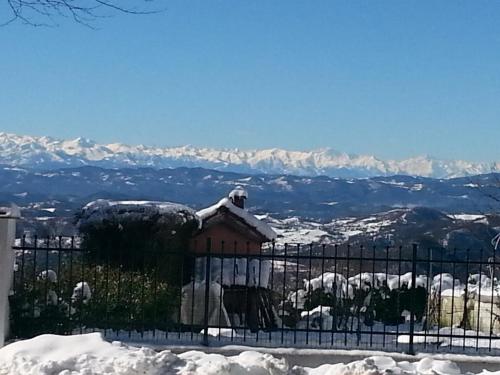a house covered in snow with mountains in the background at Relais Ristorante Sanfront in Ponzone