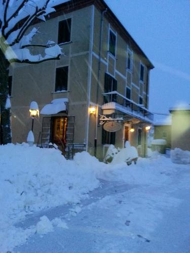 a building with snow on the ground in front of it at Relais Ristorante Sanfront in Ponzone