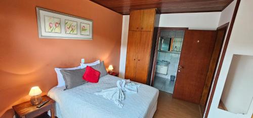 a bedroom with a bed with red and white pillows at Pousada D' Paula in Campos do Jordão