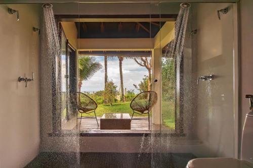 two chairs sitting in front of a window in a bathroom at Casa Sapucaia Trancoso - Cond. Vale do Segredo in Porto Seguro