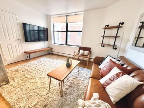 Una sala de estar con un sofá de cuero marrón y una mesa. en Charming Hoboken, a few Minutes to Manhattan, en Hoboken